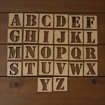 alphabet stencils laid out with crayons and pens for creative tracing activity
